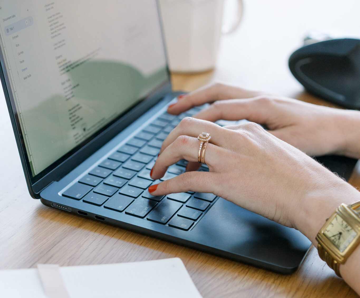 Two hands typing on a dark laptop